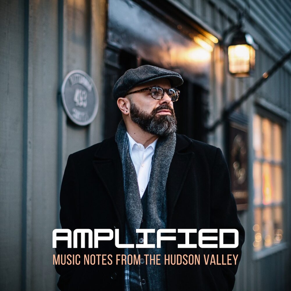 Jeremy Baum on the street in front of a venue with "AMPLIFIED" written across the bottom.