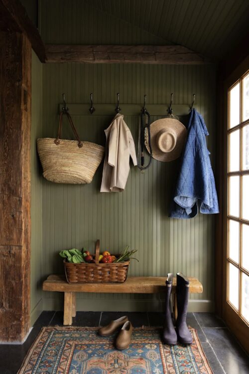 The entrance mud room with bag, coat, hat hanging on hooks and boots with a bench of the kitchen sink at 809 North Quaker Hill Road, Pawling NY.