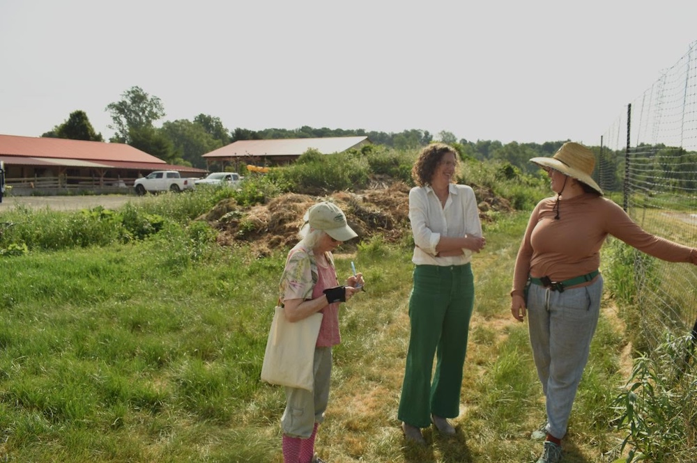 Agricultural Services Coordinator Deborah DeWan and County Executive Jen Metzger at a flower farm talking to a farmer.