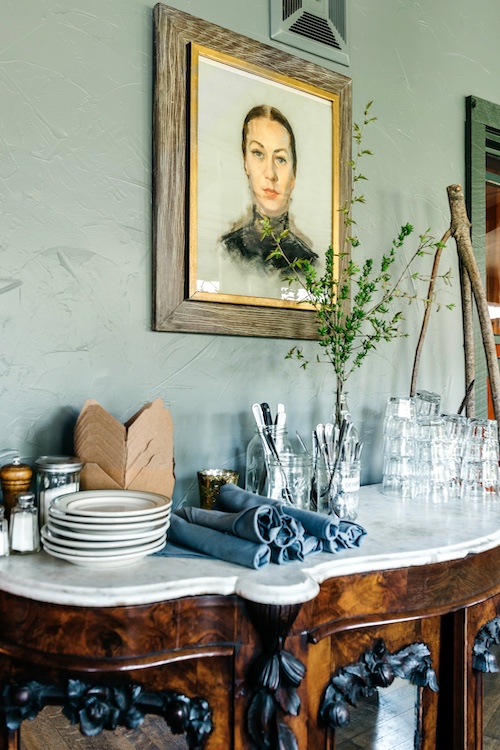 A framed image of a woman above the buffet table of plates and napkins at The Pines in Mount Tremper NY.