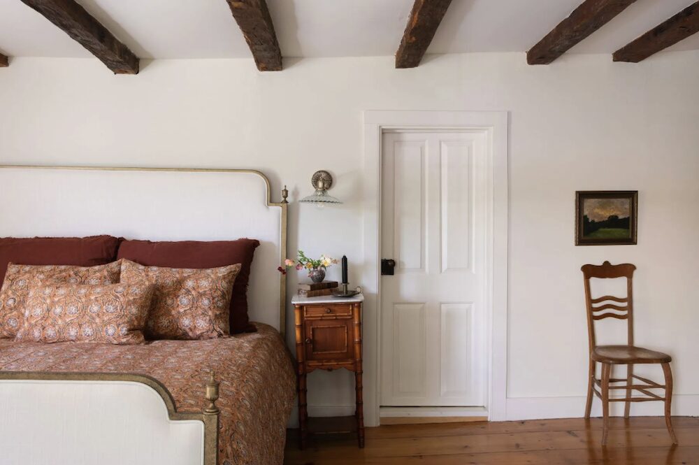 A bed with a side table, lamp and chair at 809 North Quaker Hill Road, Pawling NY.
