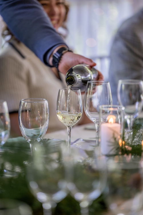 the server is pouring wine into a glass at Hudson Valley Wine Dinners at Mohonk Mountain House in New Paltz NY.