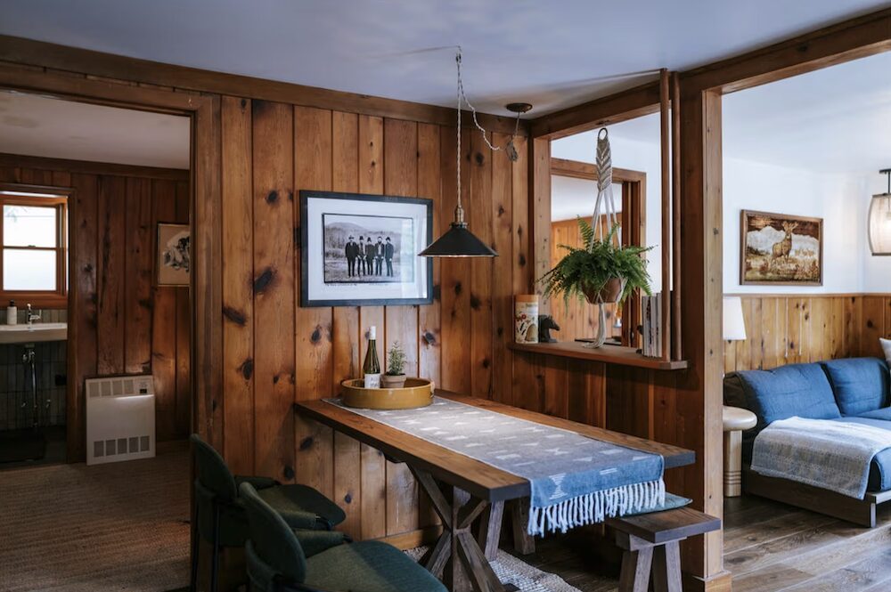 The interior of a wooden cabin with dining nook, bed and living spaces at The Leeway in Mount Tremper NY.