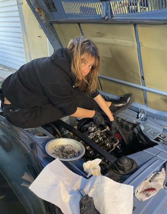 Fiona Dourif working on a car engine.