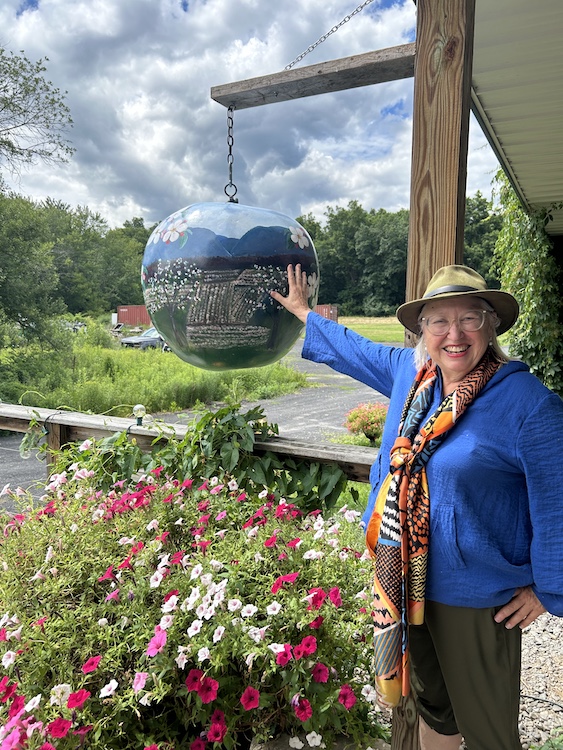 Elizabeth Ryan at Stone Ridge Orchard touching a painted apple globe.