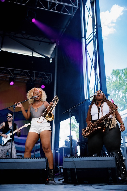 Band members singing and playing the horns for Cimafunk at the Hudson River Music Festival in Croton Point Park NY.