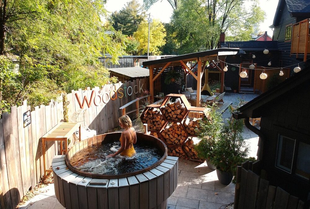 A woman standing in a hot tub in the back yard at The Herwood Inn in Woodstock NY.
