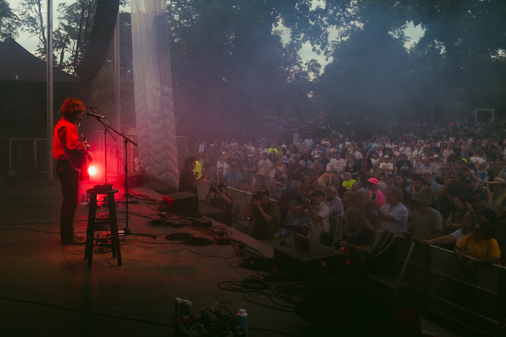Jesse Welles on stage performing in front of a crowd at the Hudson River Music Festival in Croton Point Park NY.