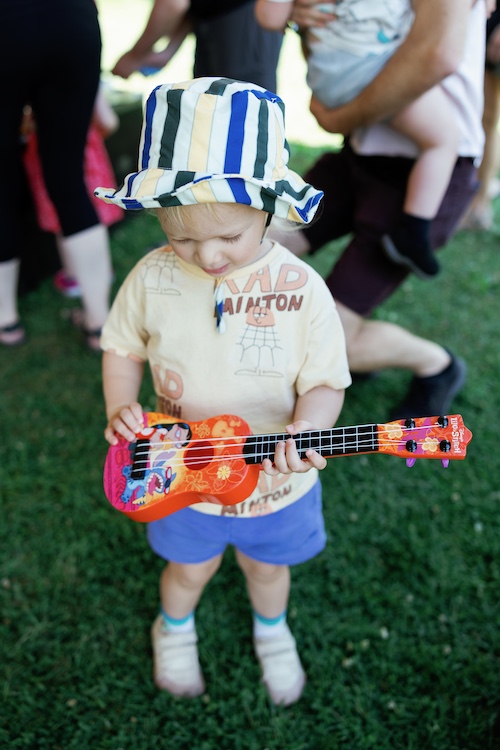 A young kid playing with a toy guitar at the Hudson River Music Festival in Croton Point Park NY.