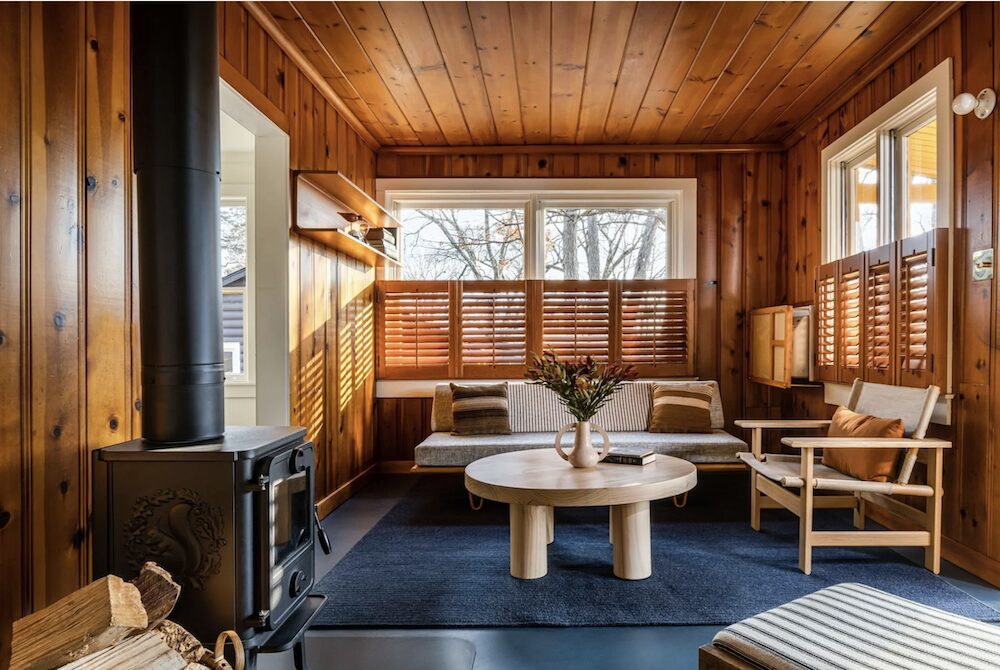 A living room with a fireplace adn wooden walls at Camptown Catskills in Leeds NY.