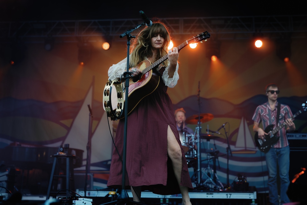 Margo Price on stage playing guitar and dancing at the Hudson River Music Festival in Croton Point Park NY.