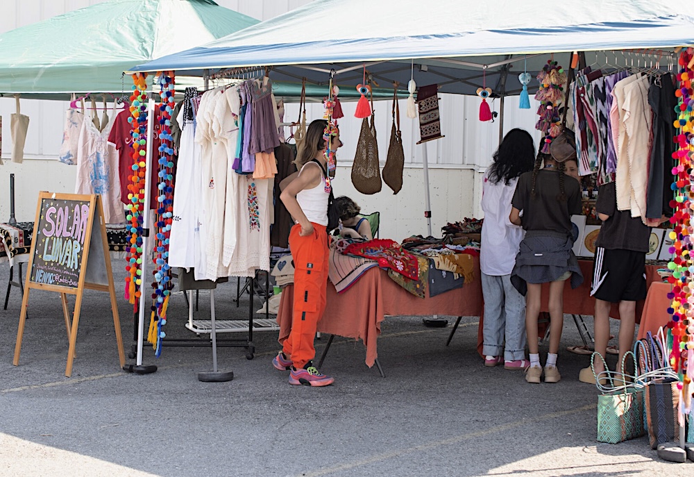 Vendor tent and customer wearing vibrant orange pants at Red Owl Flea in Kingston, NY.