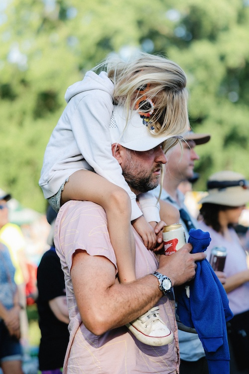 A Dad with a sleeping kid on his shoulders while watching the show at the Hudson River Music Festival in Croton Point Park NY.