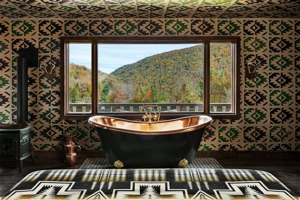 Brass bathtub and view of the mountains through a large window at Urban Cowboy in Big Indian NY.