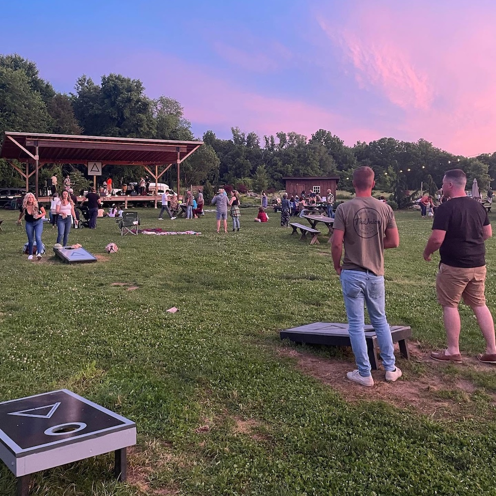 People hanging out playing cornhole on the lawn at Arrowood Farms Brewery & Distillery in Accord NY.