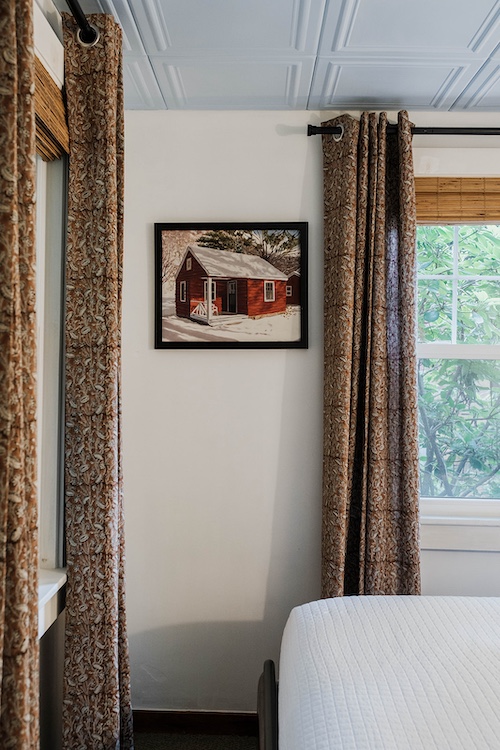 A painitng of a red cabin on the wall inside the cabin bedroom at Phoenicia Lodge in the Catskills.