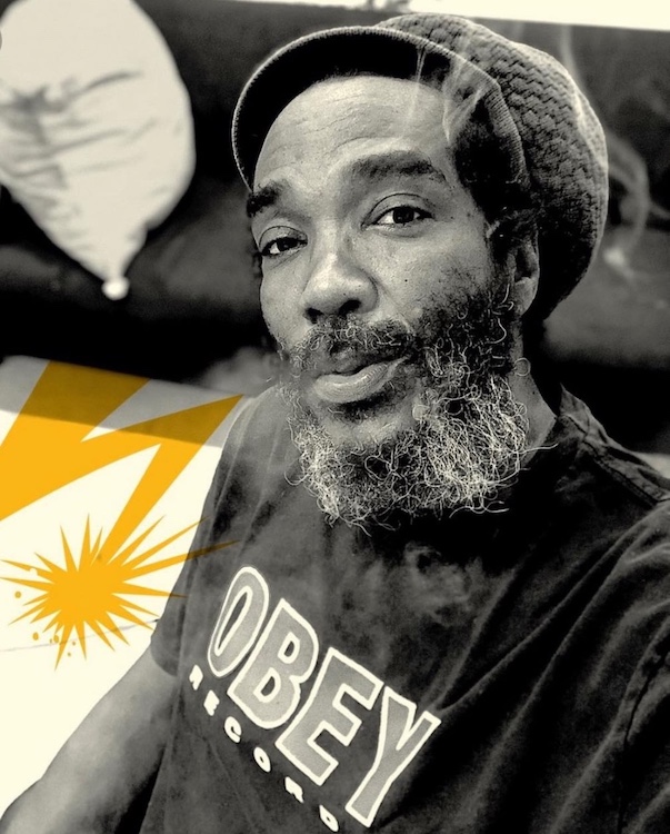 Darryl Jenifer wearing an "Obey" shirt with art beside him.