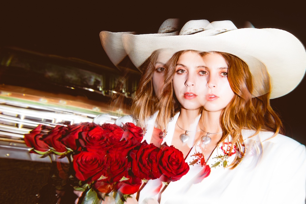 Mikaela Davis in a white suit with red hearts and bouquet of roses and white cowgirl hat