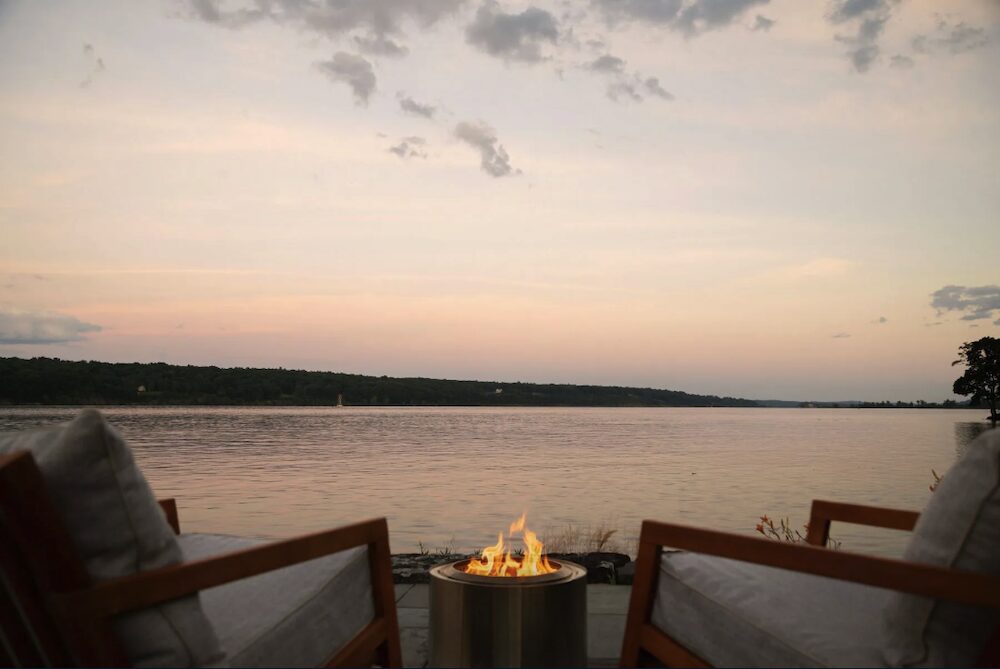Deck view of the Hudson River with a fire and chairs at 63 River Road, Malden NY.