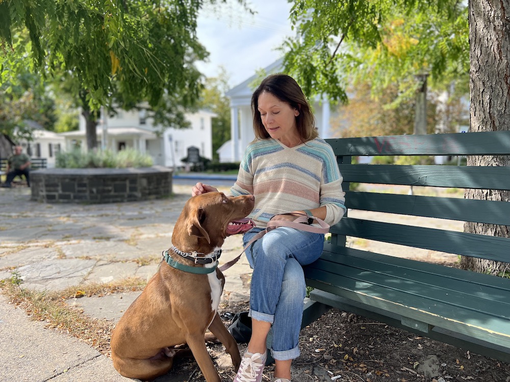 Lisa Bonk of Grateful Pups Training with Doc on a bench.
