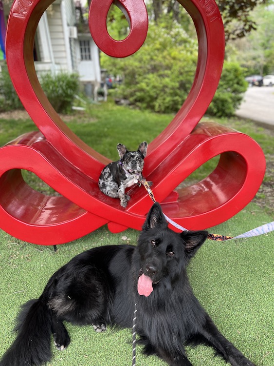 Lovie and Max in front of red heart sculpture.