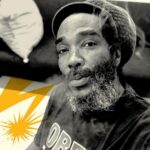 Darryl Jenifer wearing an "Obey" shirt with art beside him.
