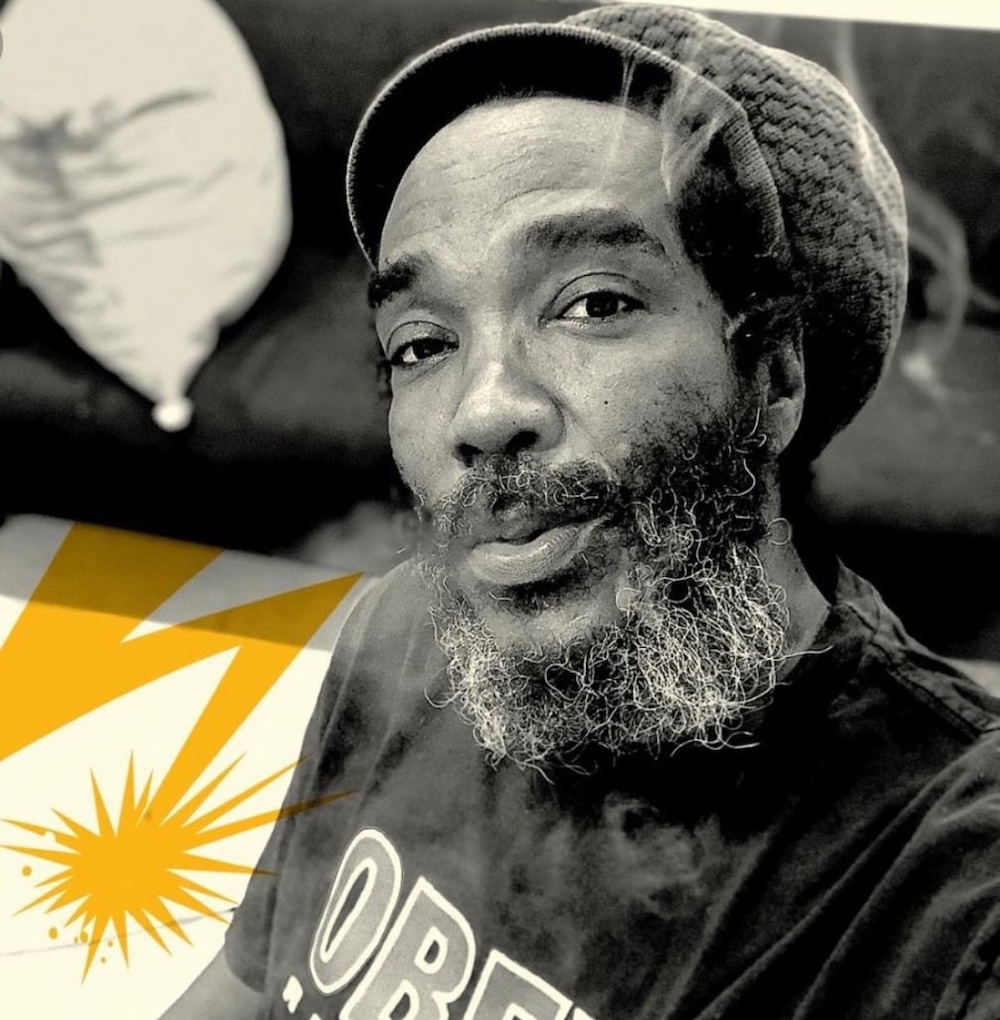 Darryl Jenifer wearing an "Obey" shirt with art beside him.