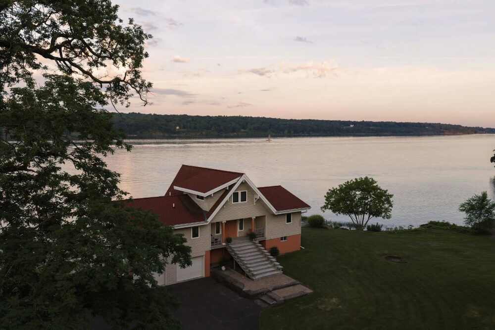 An aerial view of the front of the house and stairs with river behind it at 63 River Road, Malden NY.